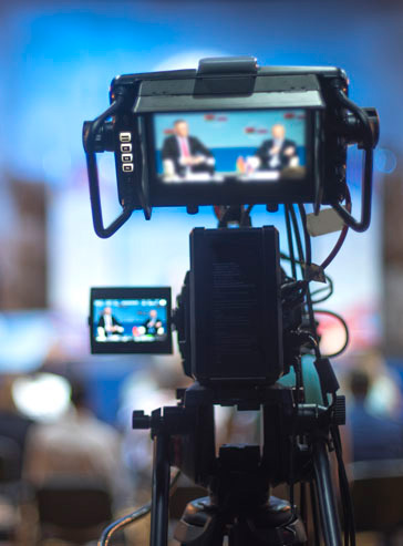 Auf dem Display einer Videokamera sieht man die Aufzeichnung einer Pressekonferenz