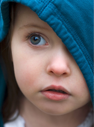 kleiner Junge schaut ängstlich unter seiner kapuze hervor