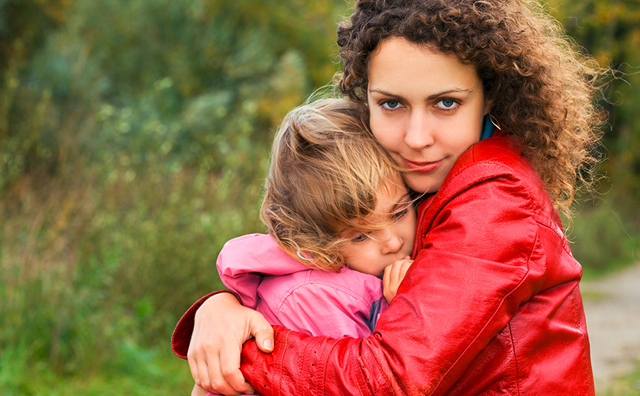 Eine junge Mutter überhütet ihre kleine Tochter