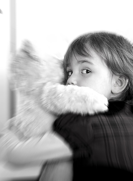 Kleiner Junge mit Teddy im Arm und ängstlichem Blick