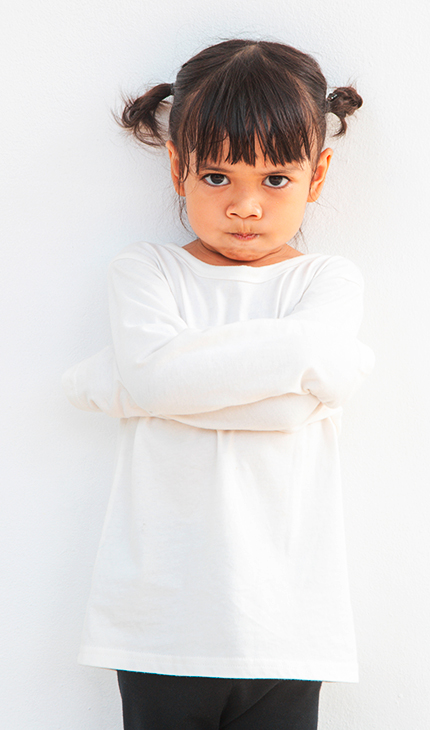 kleines Mädchen schaut bockig und hält ihre Arme verschränkt vor ihrem Körper