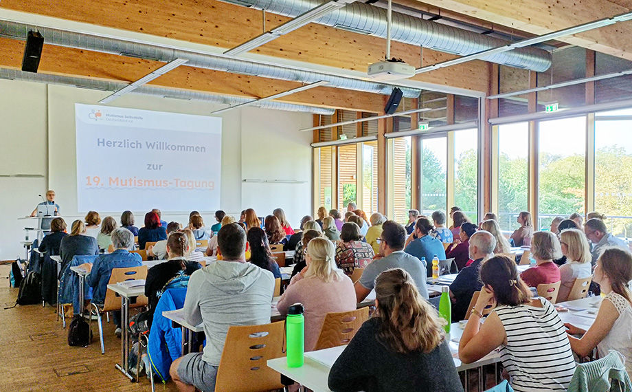 Das Foto zeigt einen vollen Saal mit Teilnehmern von hinten und der Moderatorin Dr. Anke Buschmann am Rednerpult,