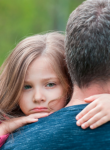 Kleines trauriges Mädchen auf dem Arm ihres Papas