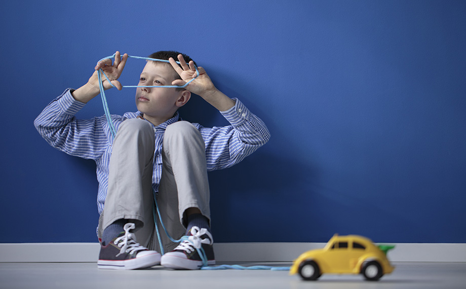 Autistischer Junge spielt gedankenversunken mit einem Band