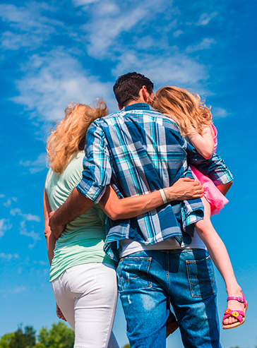 Das Foto zeigt Mutter, Vater und eine Tochter auf dem Arm ihres Vaters von hinten