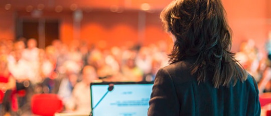 Eine Frau spricht bei einer Konferenz vor Publikum