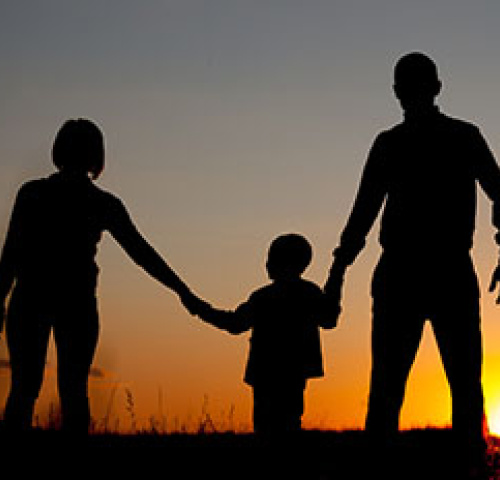 Eltern mit Kind schauen sich einen Sonnenuntergang an