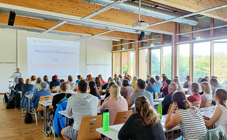 Das Foto zeigt einen vollen Saal mit Teilnehmern von hinten und der Moderatorin Dr. Anke Buschmann am Rednerpult,